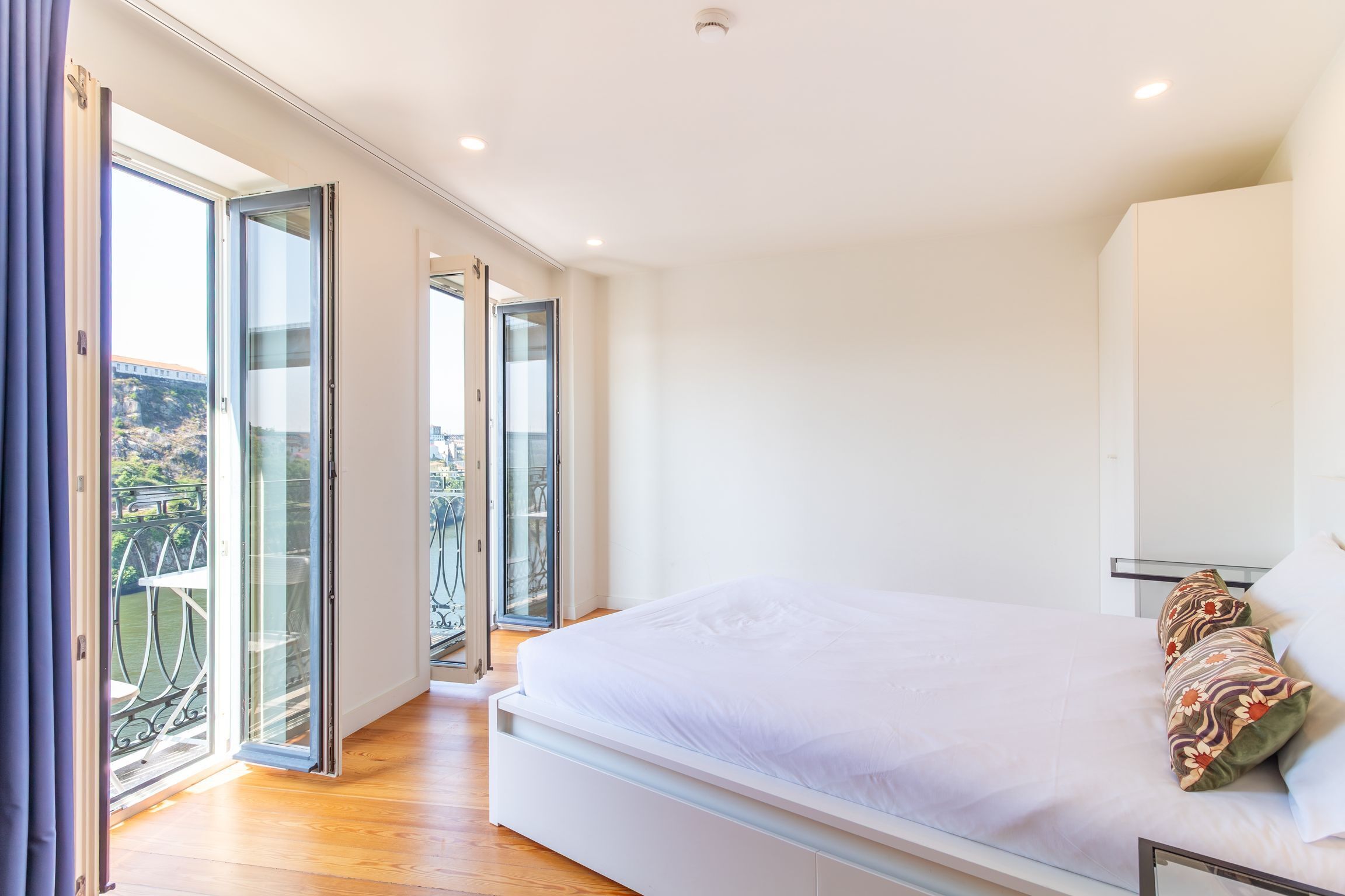 Un dormitorio con una cama grande, un balcón y vistas de la ciudad.