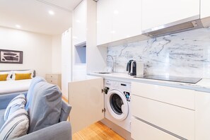 A compact kitchen with a built-in washing machine, a sink, and a countertop. - Corticeira Living (Porto)
