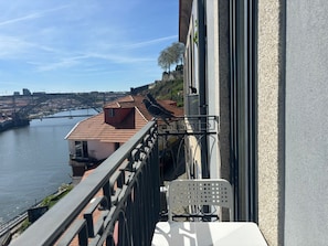 A balcony with a view of a river, a bridge, and buildings. - Corticeira Living (Porto)