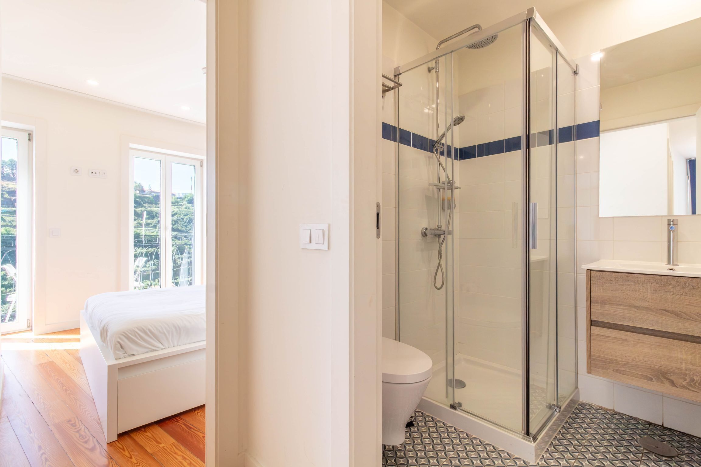 Et moderne badeværelse med et glasbrusekabine, toilet og håndvask med spejl.
