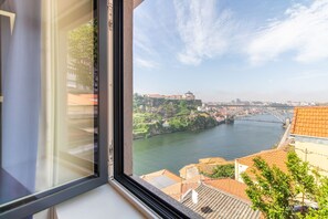 A view from a window overlooking a river with buildings and a bridge. - Corticeira Living (Porto)