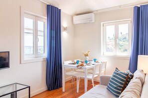 A compact living space with a dining area, a sofa, and a TV. - Corticeira Living (Porto)