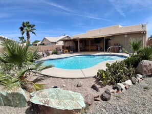 A swimming pool with a patio area, surrounded by desert plants and rocks. - Desert Sunshine Lagoon, Beautiful 2 bed 2 bath house with pool and amazing patio (Yuma)