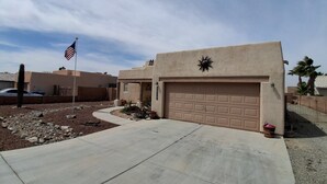 A residential area with a garage, a flag, and a cactus. - Desert Sunshine Lagoon, Beautiful 2 bed 2 bath house with pool and amazing patio (Yuma)