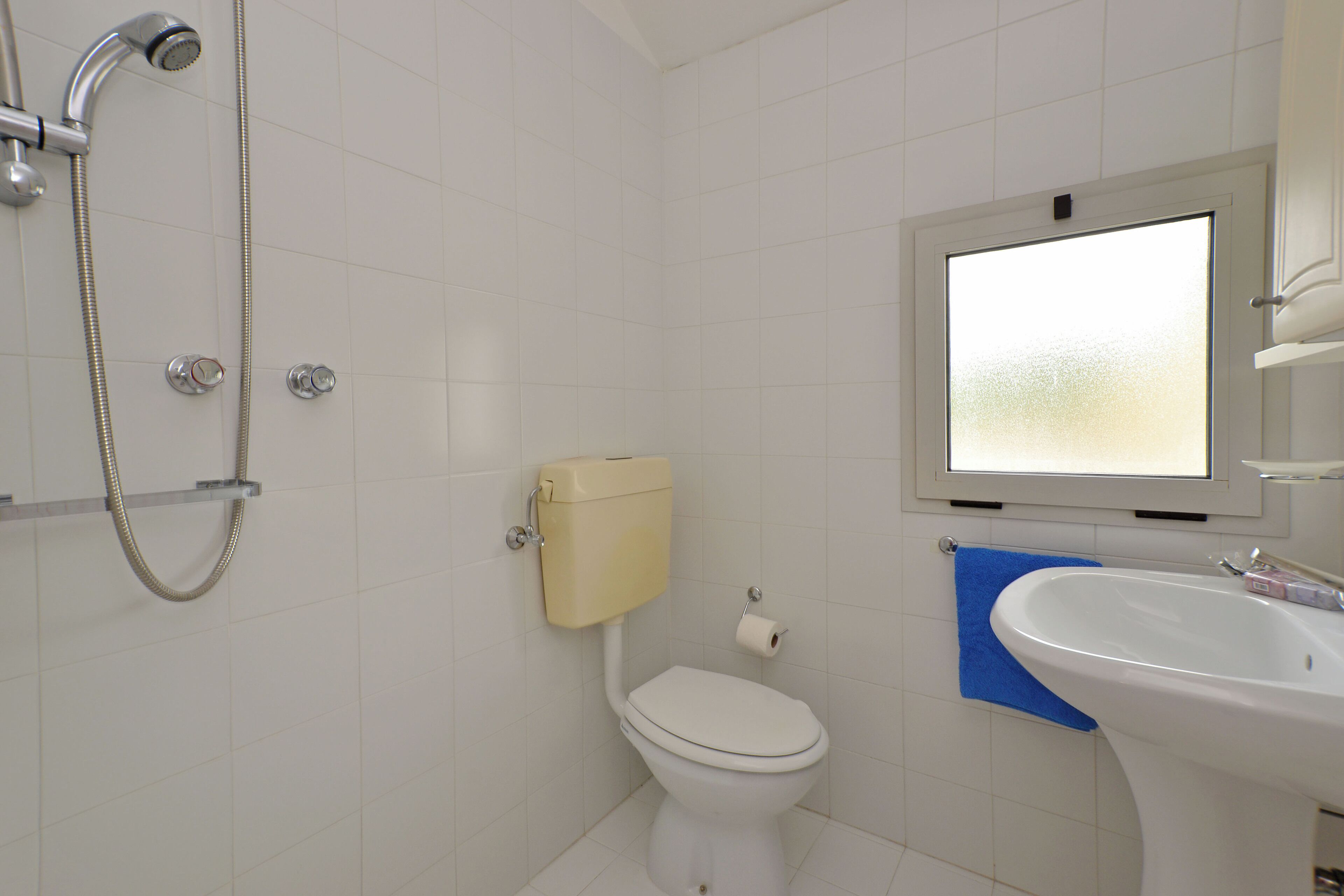 Un baño con inodoro, ducha, lavabo y ventana.