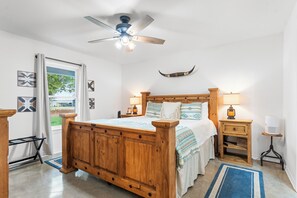 A bedroom with a wooden bed, a ceiling fan, bedside lamps, and a rustic decor theme. - Lakefront!  Fire Pit, Kayaks, Foosball, Sparkling Clean Hot Tub (Granbury)