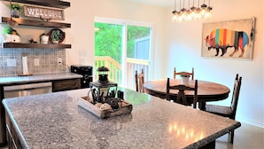 A kitchen with granite countertops, a welcome sign, a lantern, and a dining area with a round table and chairs. - Lakefront!  Fire Pit, Kayaks, Foosball, Sparkling Clean Hot Tub (Granbury)