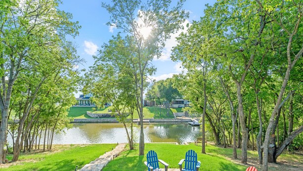 A lakeside patio with Adirondack chairs, a fire pit, and a stone pathway. - Lakefront!  Fire Pit, Kayaks, Foosball, Sparkling Clean Hot Tub (Granbury)