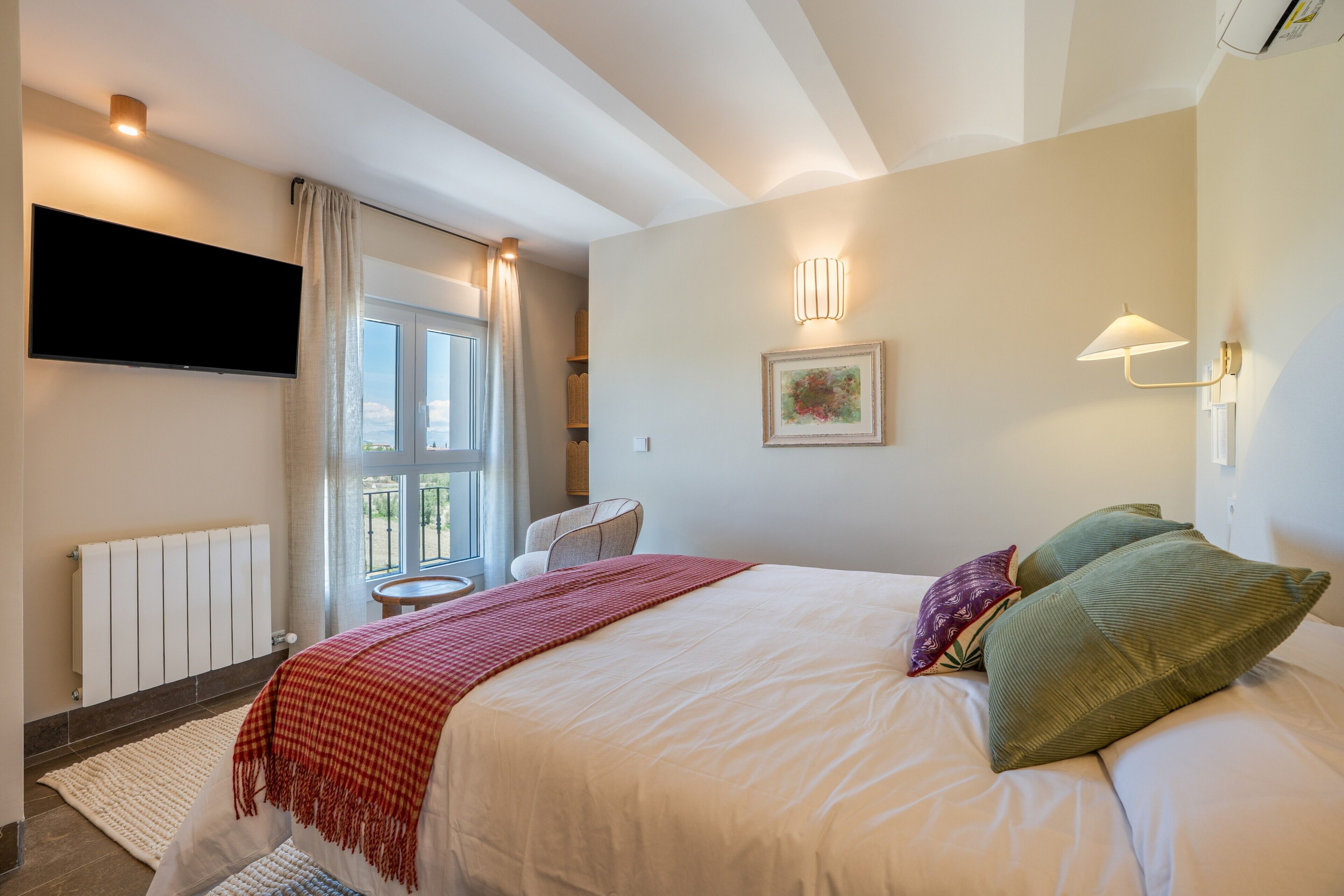 Une chambre d’hôtel avec un lit, une télévision, une fenêtre et une chaise.
