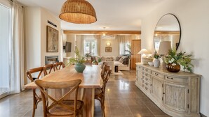 A spacious dining area with a wooden table and chairs, a buffet cabinet, and a large mirror on the wall.