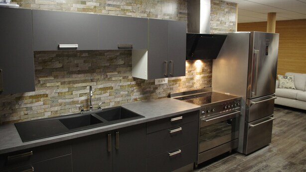 A modern kitchen with a stone backsplash, stainless steel appliances, and a built-in oven.