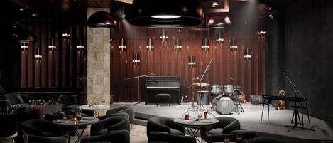 A modern lounge area with seating, a piano, a drum set, and a keyboard.