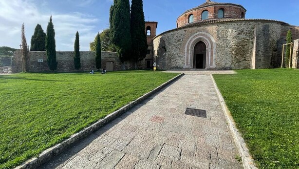 Un edificio storico con un cortile centrale, pareti in pietra e un vialetto lastricato che conduce all'ingresso.
