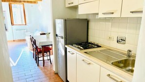 Una cucina con mobili bianchi, un lavello in acciaio inossidabile e un piano cottura a gas.