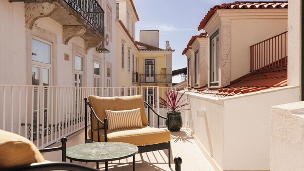 A balcony with a chair, a small table, and a potted plant. - Ando Living - Fanqueiros House (Lisbon)