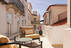 A balcony with a chair, a small table, and a potted plant. - Ando Living - Fanqueiros House (Lisbon)