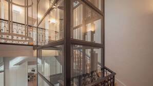 A multi-level interior with glass railings, a staircase, and a dining area. - Ando Living - Fanqueiros House (Lisbon)