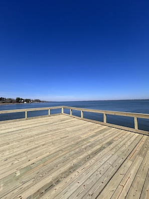 Un muelle de madera que se extiende sobre aguas tranquilas, bajo un cielo despejado.