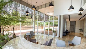 A spacious lobby with a curved seating area, large windows, and modern pendant lighting. - Apartamento Urban Studios (Medellín)