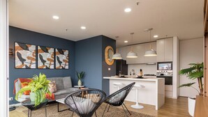 A modern kitchen with white cabinets, a central island, and pendant lighting. - Apartamento Urban Studios (Medellín)