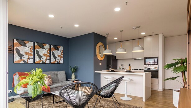 A modern kitchen with white cabinets, a central island, and pendant lighting. - Apartamento Urban Studios (Medellín)