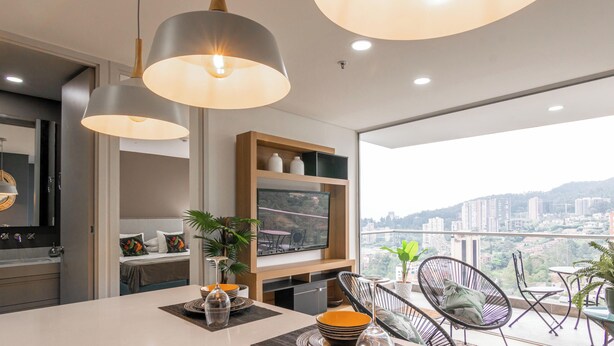 A modern kitchen with a large window, a dining area with chairs, and a view of a cityscape. - Apartamento Urban Studios (Medellín)
