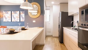 A modern kitchen with a central island, stainless steel appliances, and pendant lighting. - Apartamento Urban Studios (Medellín)