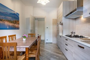 Una cocina moderna con comedor, sillas de madera, una mesa y un cuadro de un paisaje.
