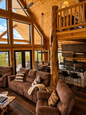 A spacious living area with a large wooden ceiling, a central wooden pillar, and a cozy seating arrangement.