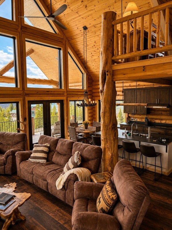 Un vaste espace de vie dotĂ© dâun grand plafond en bois, dâun pilier central en bois et dâun coin salon confortable.