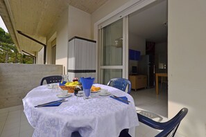 A round table with a white tablecloth, blue napkins, and cutlery, set for dining. - Quiet Living for Your Vacation (Lignano Sabbiadoro)