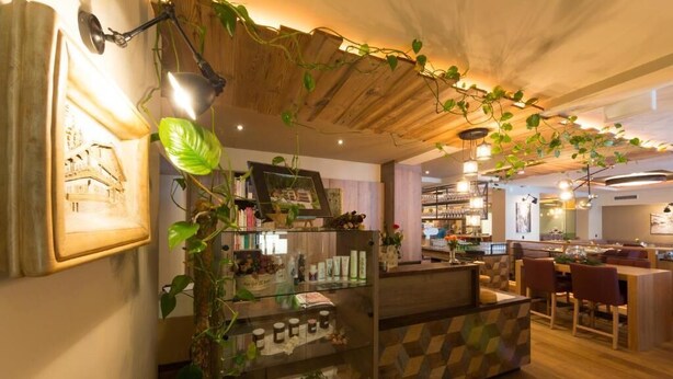 Ein gemütliches Café mit Holzbalkendecke, einer Glasvitrine mit Waren und einer Holztresen.