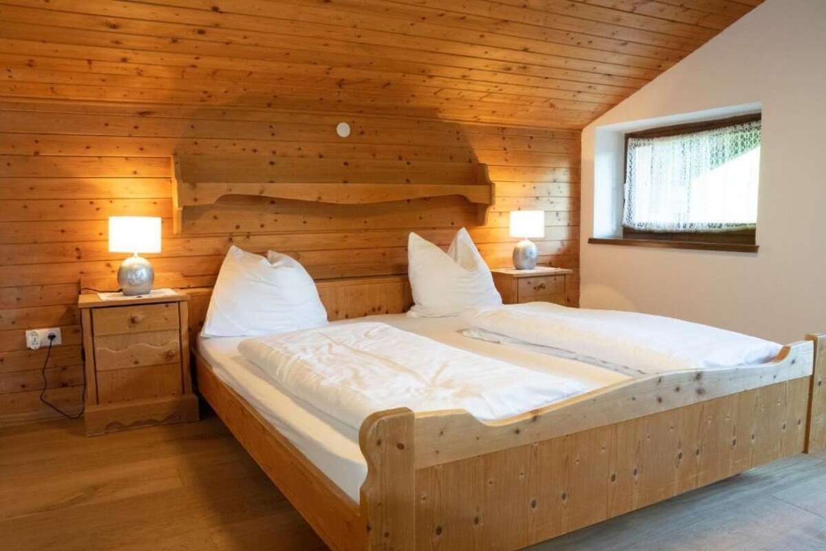 Una cama litera de madera con dos mesitas de noche, cada una con una lámpara.