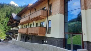 Ein mehrstöckiges Hotel mit hölzernen Balkonen, großen Fenstern und Blick auf einen bewaldeten Berg.