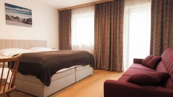 Una camera d'albergo con un letto, un divano, una poltrona e un quadro appeso al muro.