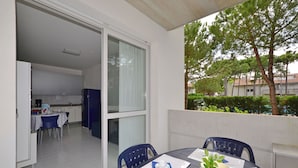 A dining area with a table, chairs, and a view of the kitchen and outside. - Cozy Stay in Lignano (Lignano Sabbiadoro)