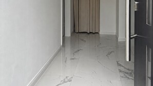 Ein Korridor mit Marmorboden, einer Tür rechts und einem Vorhang in der Ferne.