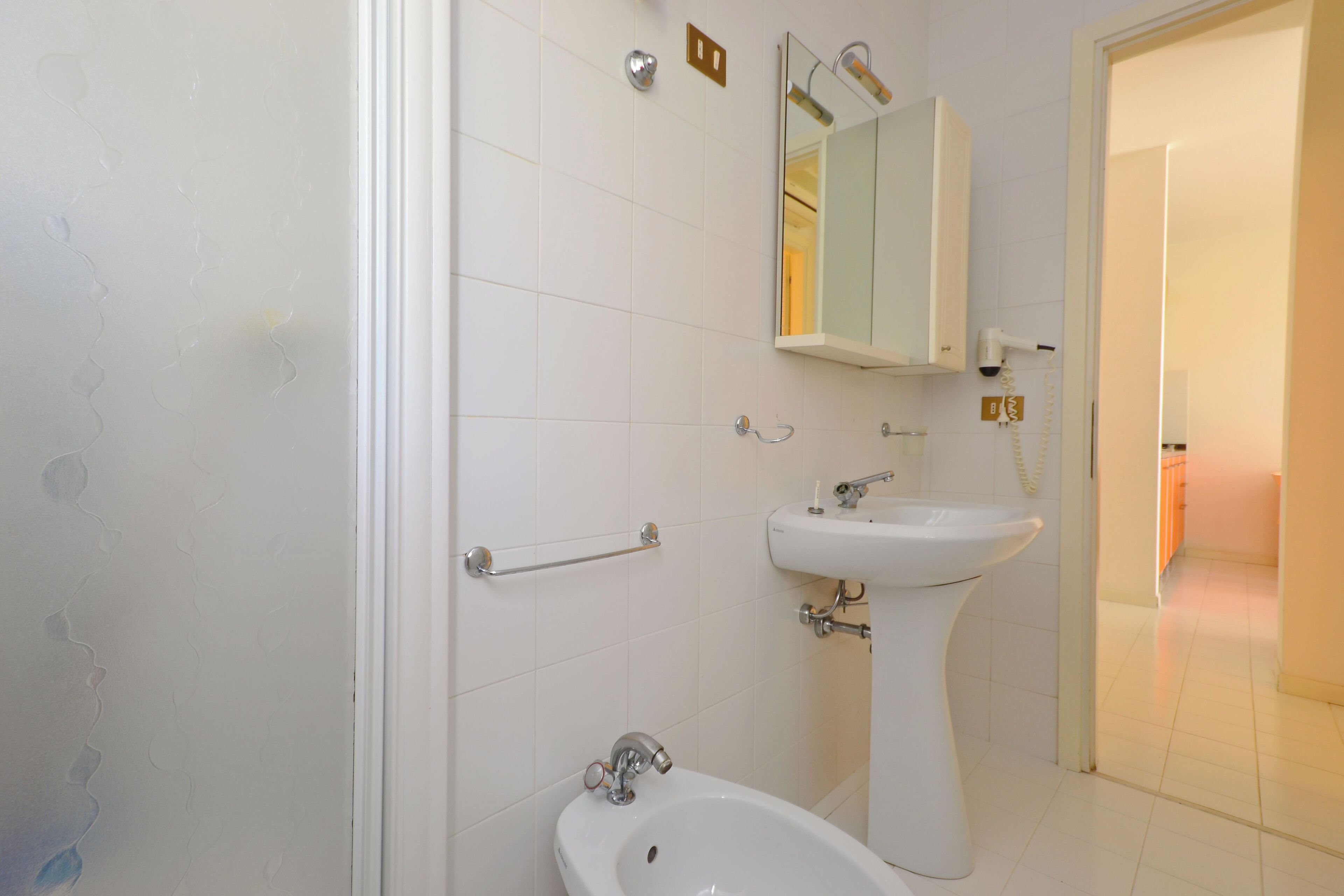 A bathroom with a bidet, a sink, and a mirror.