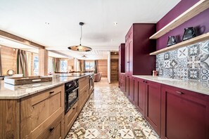 Eine moderne Küche mit Holzschränken, einer Marmorarbeitsplatte und fliesenbelagtem Boden mit Muster.