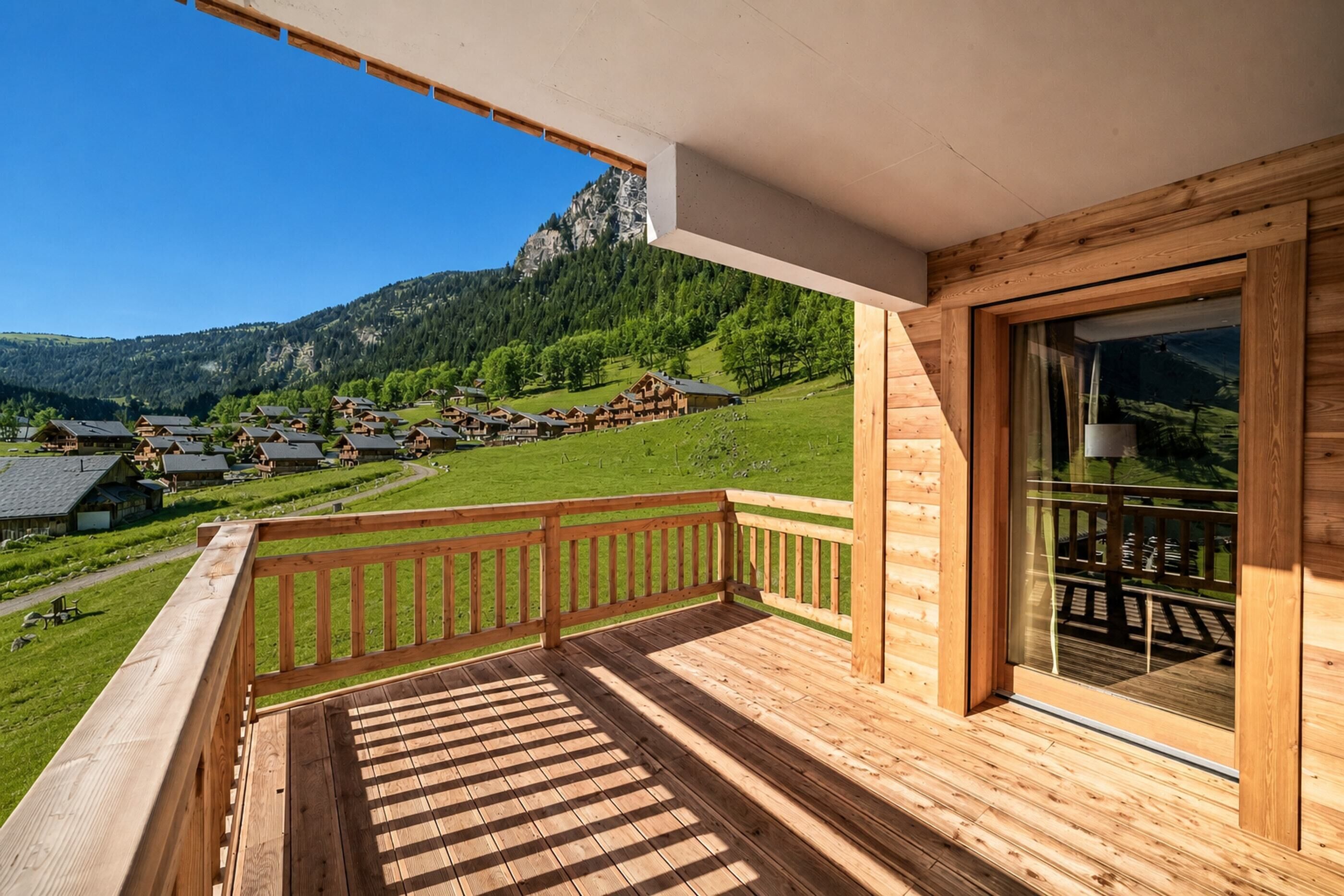 Eine Holzterrasse mit Blick auf ein dörfliches Bergpanorama.