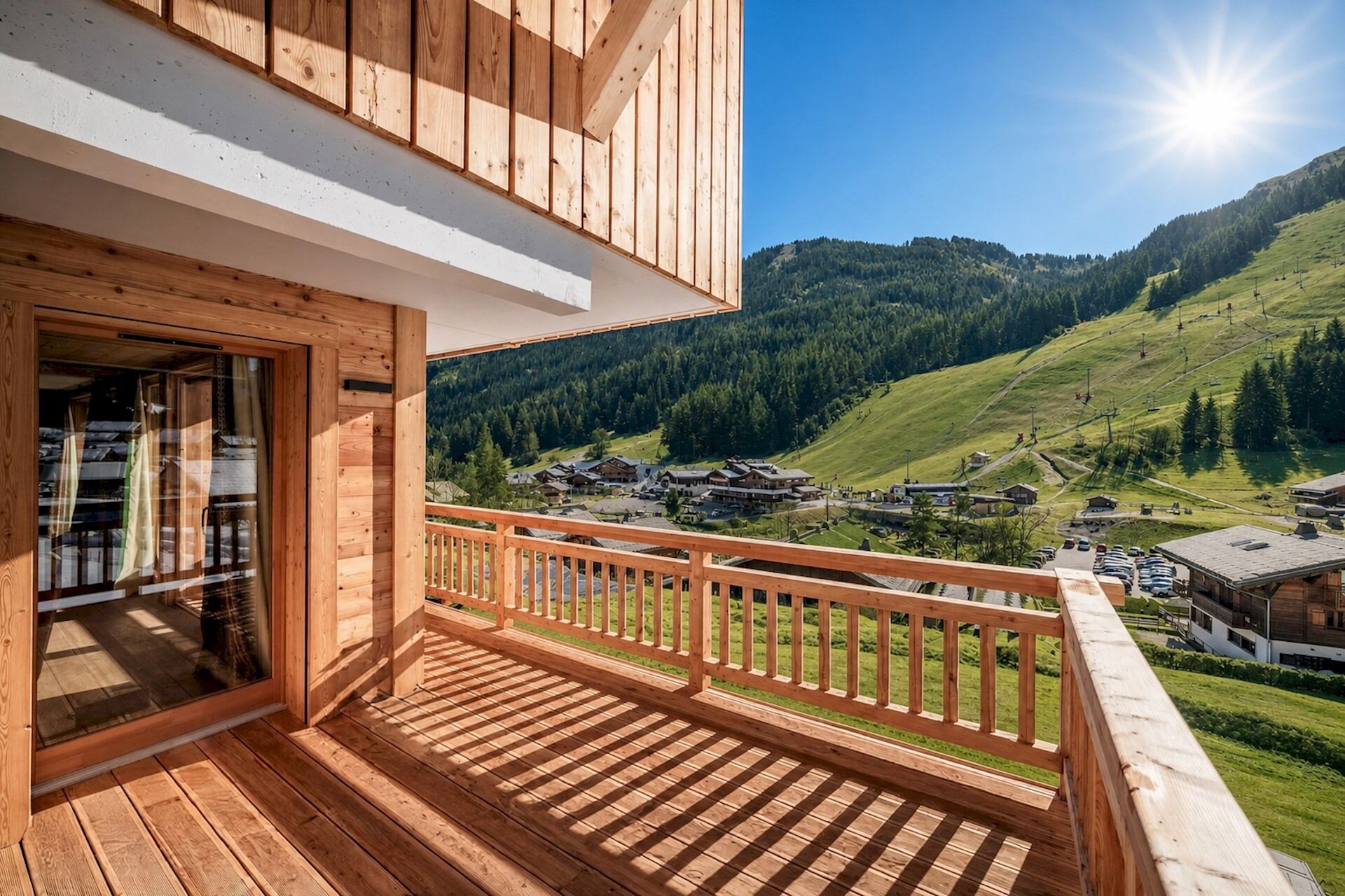 Een houten balkon met uitzicht op een bergachtig landschap en een dorp beneden.