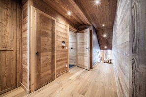 Ein hölzerner Innenbereich mit einer Holztür, einem kleinen Fenster und einem Klingel.