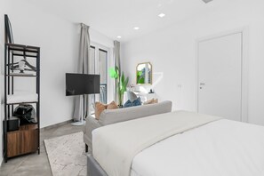 A modern hotel room with a bed, a television, a desk, a mirror, and a wardrobe. - Penthouse "Vivi Milano" in Duomo District + Comfort (Milano)