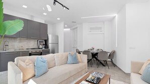 A modern living room with a sofa, coffee table, and dining area. - Penthouse "Vivi Milano" in Duomo District + Comfort (Milano)