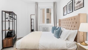 A bedroom with a bed, a wardrobe, a radiator, a window with curtains, and framed pictures on the wall. - Penthouse "Vivi Milano" in Duomo District + Comfort (Milano)
