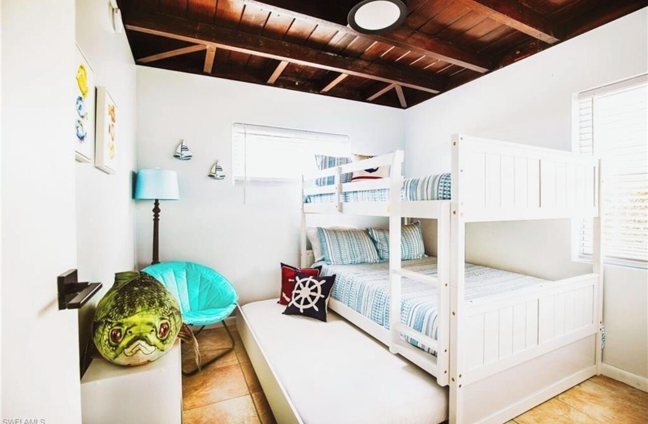 Ein Zimmer mit Etagenbetten, einem Sessel, einer Lampe und einer Wand mit maritimer Dekoration.