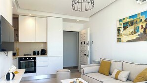 Un espacio habitable moderno con cocina, sofá, mesa de centro y un cuadro en la pared.