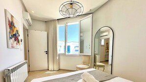 Habitación de hotel moderna con una cama grande, un espejo, un radiador y una ventana con cortinas.