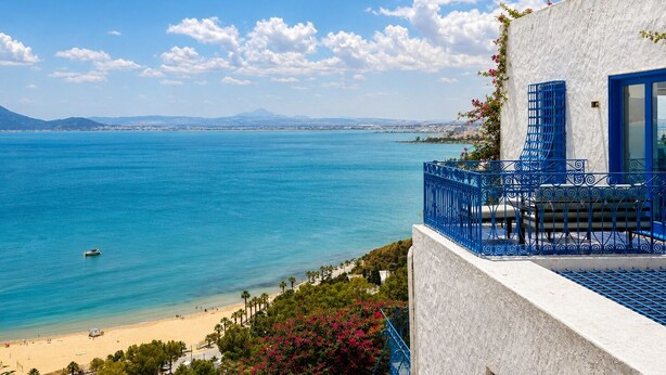 Vista costera con cielo despejado, una playa y un edificio con balcón.