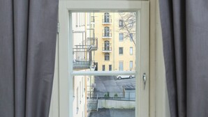 A window with a view of a yellow building with multiple balconies and a parked car outside. - Premium 4-Bedroom Stay in Central Helsinki (Helsinki)